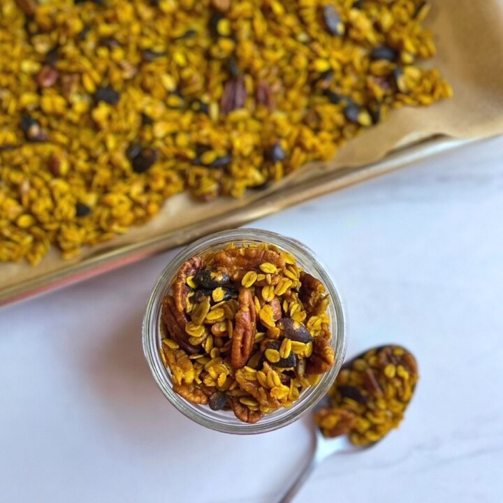 Overhead shot of a jar of Golden Spiced Granola next to a sheet pan of granola