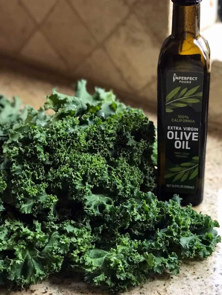 Up close shot of curly kale leaves and a bottle of olive oil