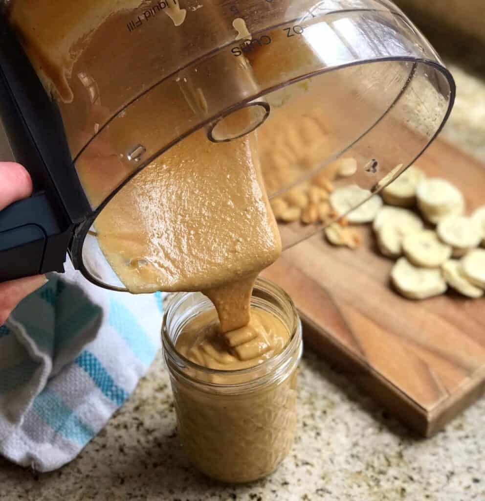 Shot of homemade banana peanut butter being poured into a glass jar