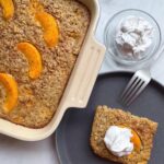 Overhead shot of a slice of Peaches and Cream Baked Oatmeal next to a pan on oats