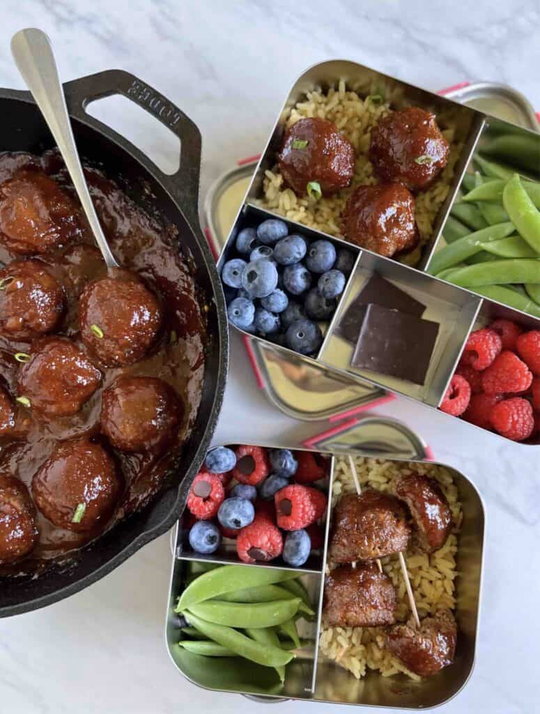 Overhead shot of Baked BBQ Beef Meatballs in a skillet and lunchboxes.